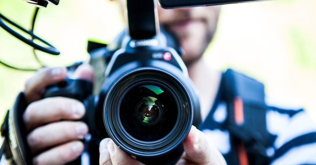 a close up shot of a cameraman filming focusing on the camera lens and equipment